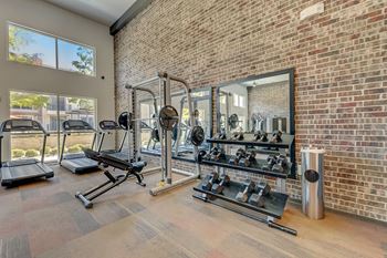 A gym with a brick wall and a variety of equipment.